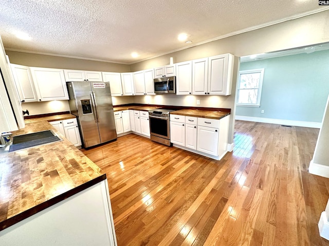 kitchen featuring stainless steel appliances, white cabinets, butcher block countertops, and light wood finished floors