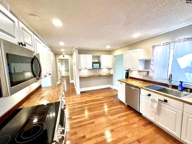 kitchen featuring open shelves, stainless steel appliances, white cabinets, a sink, and wood counters