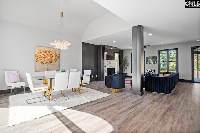 dining space featuring recessed lighting, a notable chandelier, a fireplace, wood finished floors, and baseboards