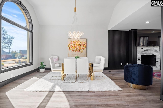 dining room with a chandelier, vaulted ceiling, a wealth of natural light, and wood finished floors