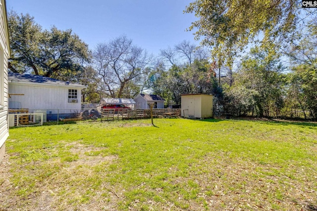 view of yard with fence, an outdoor structure, and a storage unit