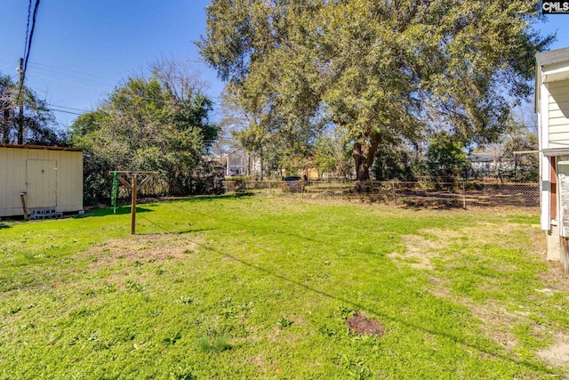 view of yard featuring an outdoor structure, fence, and a shed