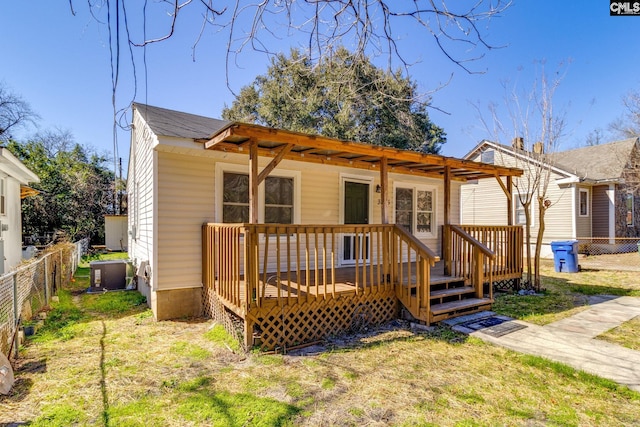 view of front of property with a front yard, fence, a wooden deck, and central air condition unit