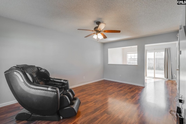 living area with a textured ceiling, baseboards, and wood finished floors