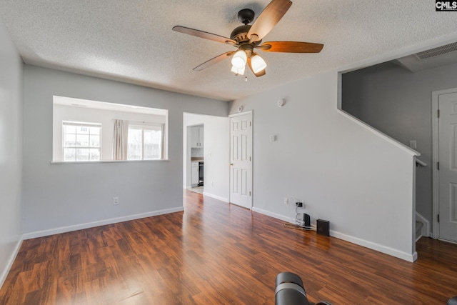 unfurnished living room featuring a ceiling fan, a textured ceiling, baseboards, and wood finished floors