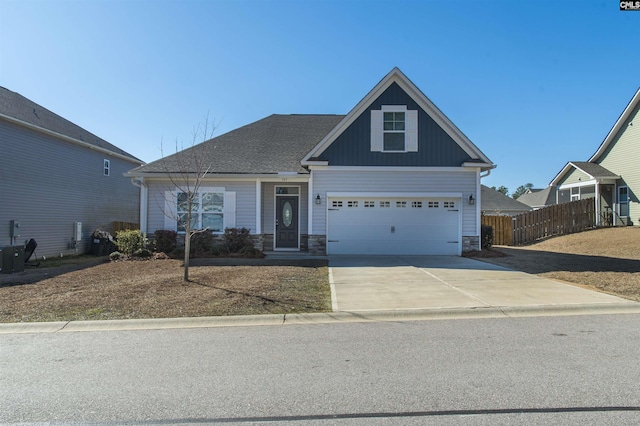 craftsman-style home with driveway, board and batten siding, stone siding, and fence