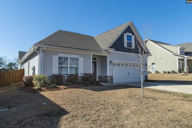 view of front facade featuring driveway, a shingled roof, stone siding, an attached garage, and fence