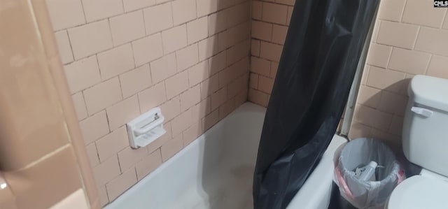 full bathroom with shower / tub combo, toilet, and tile walls