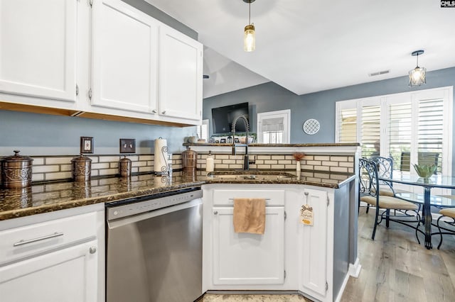 kitchen with visible vents, white cabinets, a sink, dishwasher, and a peninsula