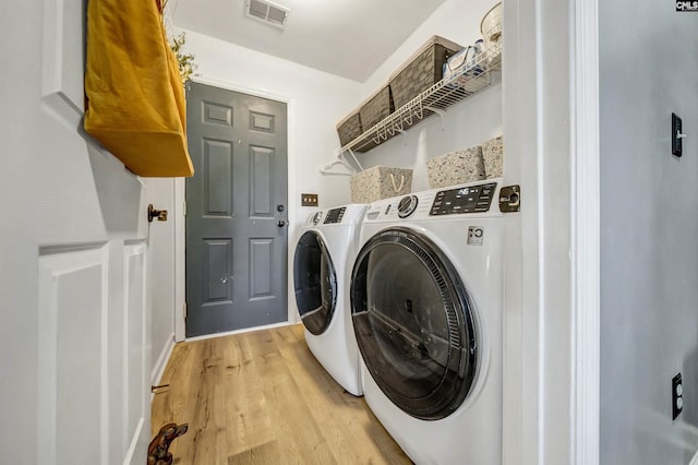 laundry room with laundry area, washer and clothes dryer, light wood-type flooring, and visible vents