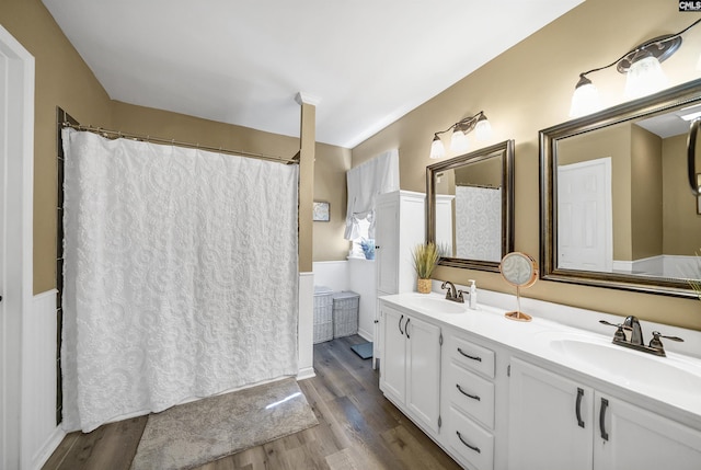 bathroom featuring double vanity, wood finished floors, and a sink