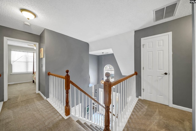 corridor with a wealth of natural light, carpet, visible vents, and an upstairs landing