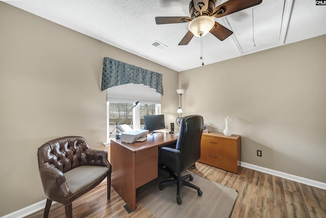 home office featuring attic access, baseboards, visible vents, wood finished floors, and a textured ceiling