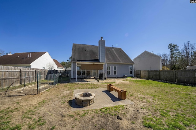 rear view of house featuring a yard, a chimney, a patio area, a fenced backyard, and a fire pit