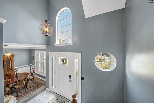 tiled entryway featuring a chandelier and a high ceiling