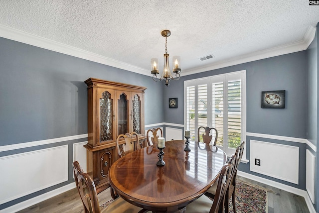 dining room featuring wainscoting, visible vents, a notable chandelier, and wood finished floors