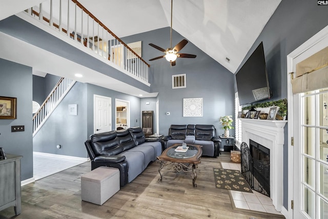 living area with a fireplace with flush hearth, visible vents, stairway, and wood finished floors