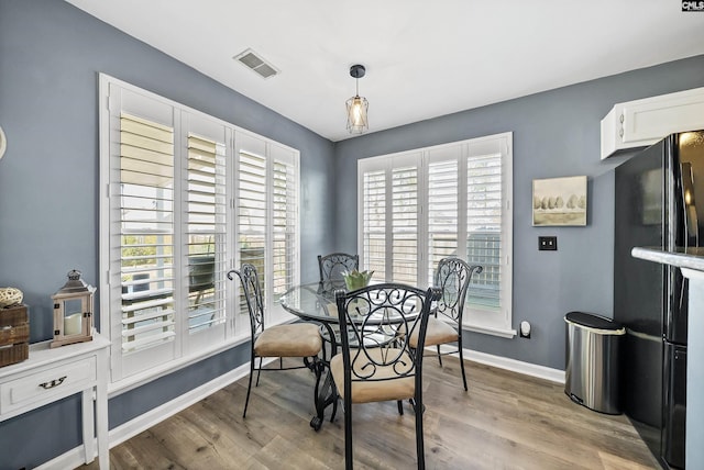 dining room featuring light wood-style floors, visible vents, and baseboards