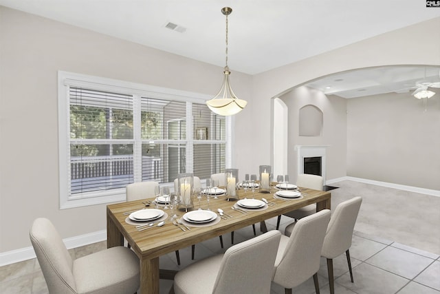 dining room with baseboards, visible vents, arched walkways, a ceiling fan, and a fireplace