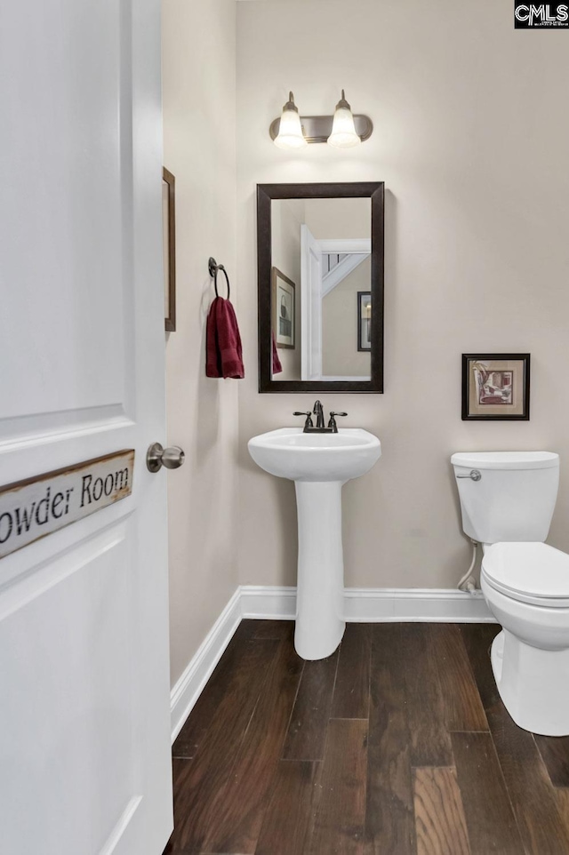 bathroom with toilet, baseboards, and wood finished floors