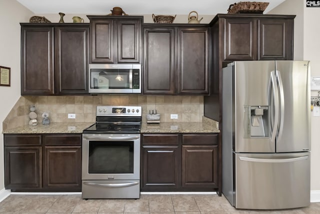 kitchen featuring stainless steel appliances, tasteful backsplash, light stone counters, and dark brown cabinetry