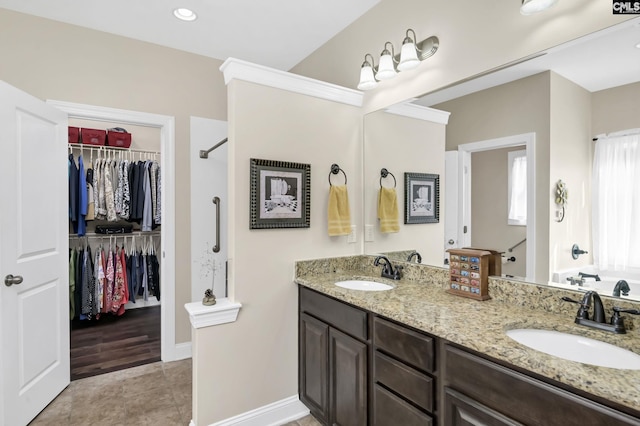 bathroom with double vanity, a spacious closet, and a sink