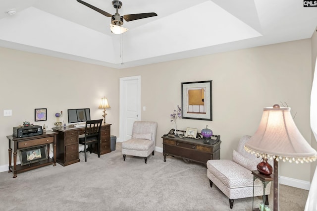 carpeted home office featuring a tray ceiling, ceiling fan, and baseboards