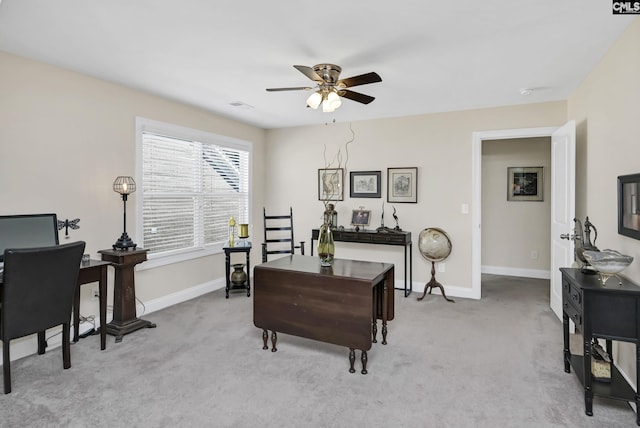 office space featuring light colored carpet, ceiling fan, visible vents, and baseboards