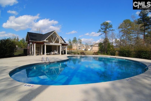 pool featuring an outbuilding, a patio, and fence