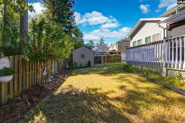 view of yard with a deck, a shed, an outdoor structure, and a fenced backyard