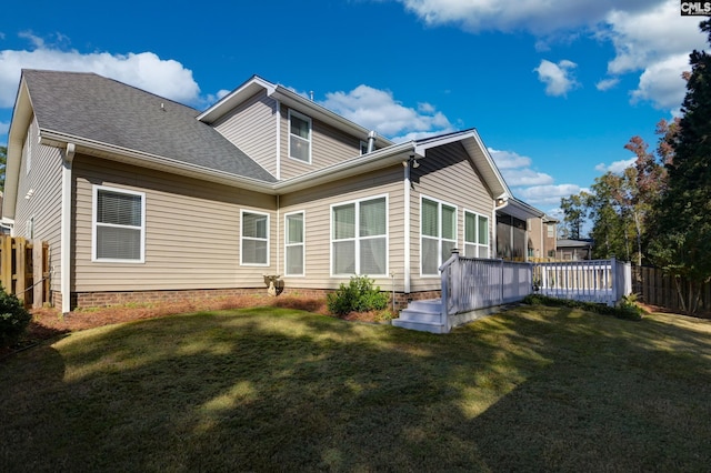 back of house featuring fence, a lawn, and roof with shingles