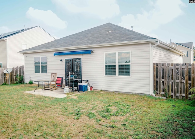 rear view of house featuring a yard, a shingled roof, a patio area, and a fenced backyard