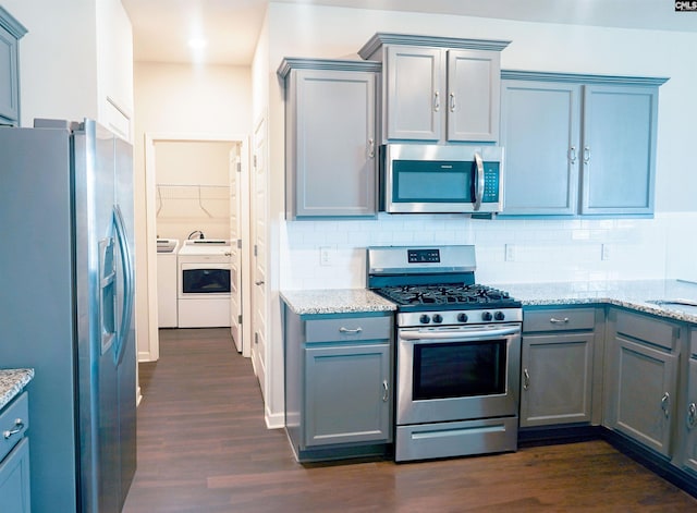 kitchen featuring gray cabinets, dark wood finished floors, stainless steel appliances, separate washer and dryer, and decorative backsplash