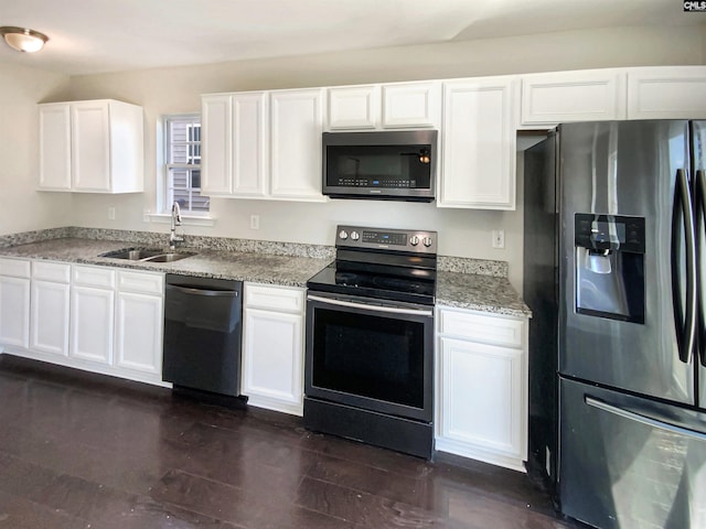 kitchen featuring light stone counters, dark wood finished floors, stainless steel appliances, white cabinetry, and a sink