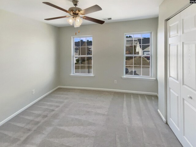 unfurnished room featuring a ceiling fan, carpet, visible vents, and baseboards