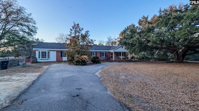 single story home with driveway, fence, a porch, and brick siding