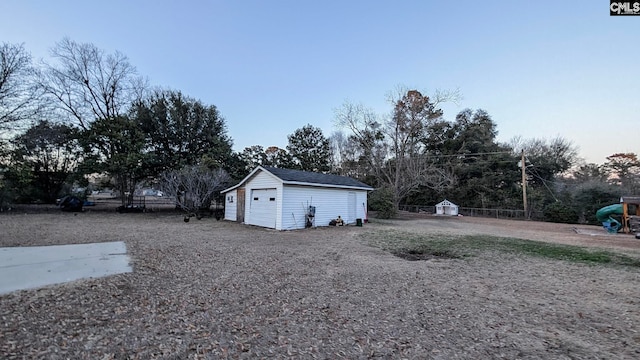 view of yard with a detached garage, fence, and an outdoor structure