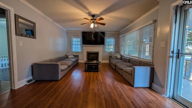 unfurnished living room with baseboards, wood finished floors, a textured ceiling, crown molding, and a fireplace