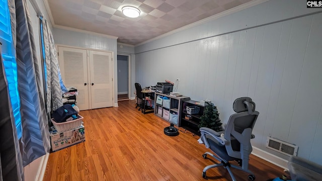 office with wood finished floors, visible vents, and crown molding