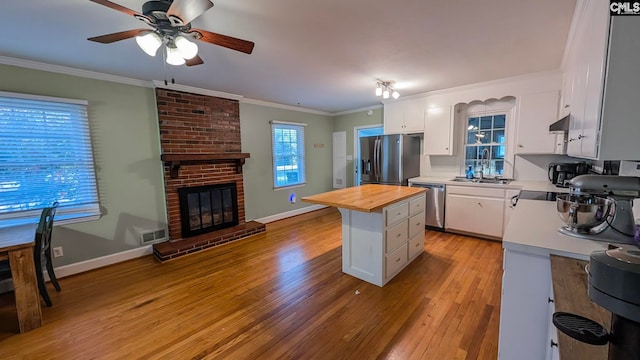 kitchen with appliances with stainless steel finishes, white cabinets, wooden counters, and ornamental molding