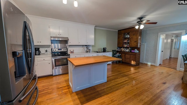 kitchen with stainless steel appliances, white cabinets, crown molding, and wood counters