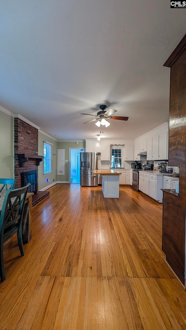 kitchen with crown molding, stainless steel appliances, open floor plan, white cabinets, and hardwood / wood-style floors