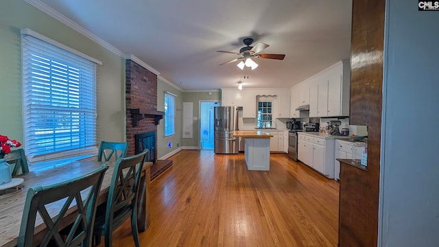 kitchen with a center island, crown molding, appliances with stainless steel finishes, white cabinetry, and wood finished floors