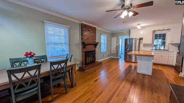 kitchen with butcher block counters, light wood-style floors, white cabinets, stainless steel fridge with ice dispenser, and a center island