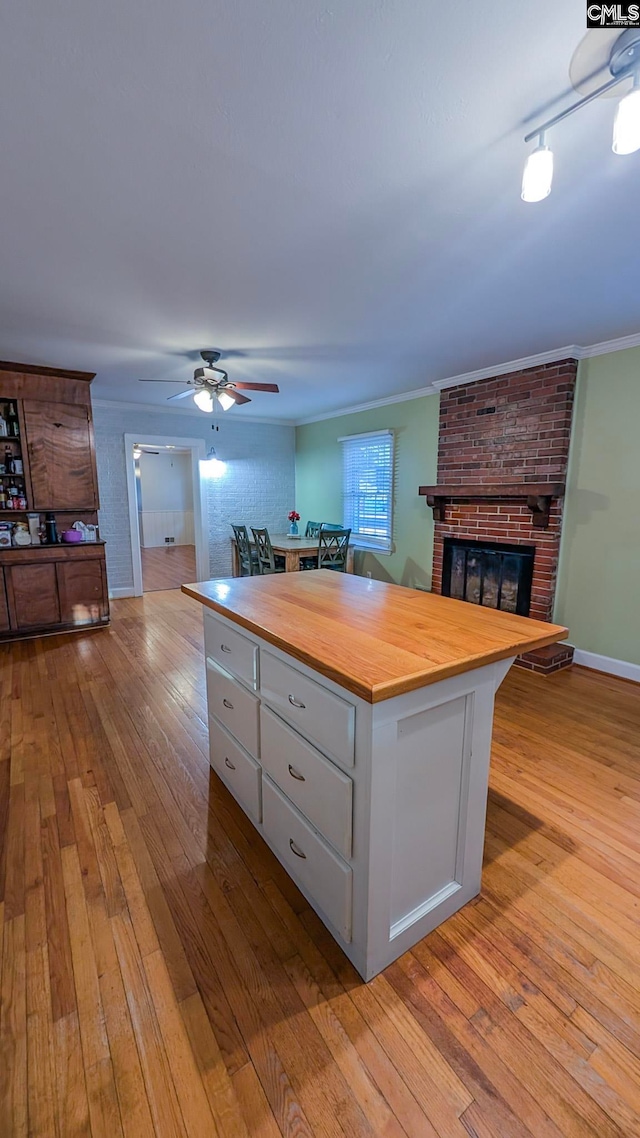 kitchen featuring a fireplace, ornamental molding, open floor plan, butcher block countertops, and hardwood / wood-style flooring