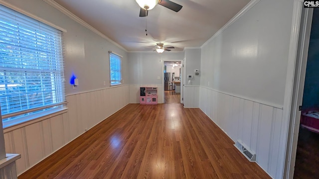 unfurnished dining area featuring a wainscoted wall, plenty of natural light, visible vents, and wood finished floors