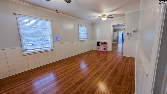 spare room featuring crown molding, wood finished floors, a ceiling fan, and wainscoting