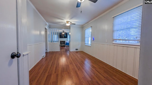 spare room featuring crown molding, a wainscoted wall, a fireplace, and wood finished floors