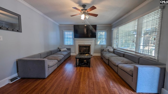 living area with ornamental molding, visible vents, a fireplace, and wood finished floors