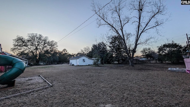 yard at dusk featuring a playground